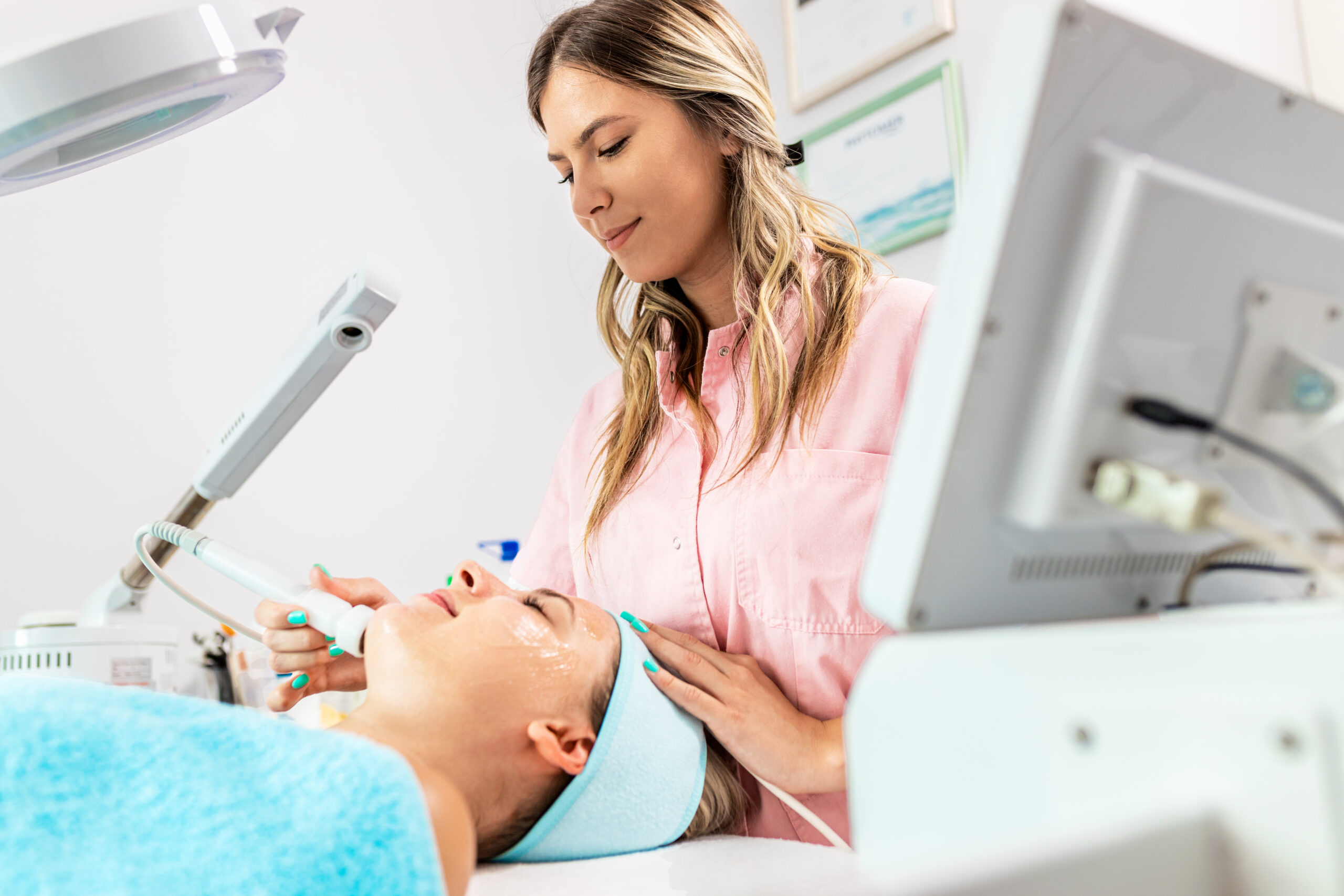 Beautician therapist applying face treatment in beauty salon to